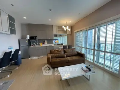 Spacious modern living room with open kitchen and large windows in a stylish apartment.