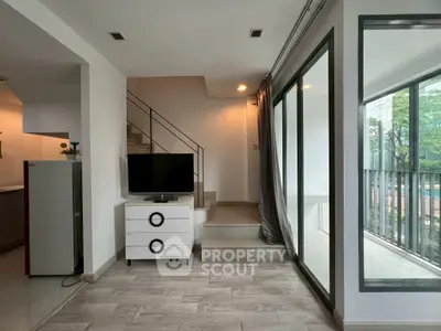 Modern living room with sleek staircase and large windows overlooking greenery.