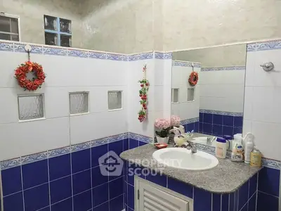 Charming bathroom with blue and white tiles, decorative accents, and modern sink.