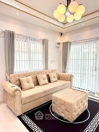 Elegant living room with plush beige sofa, modern lighting, and large windows with curtains.