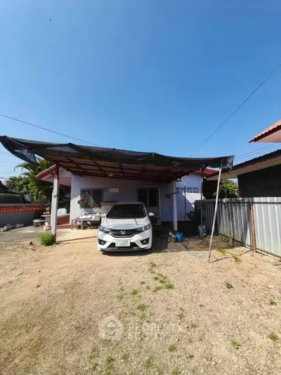 Charming single-story home with carport and spacious yard under clear blue sky.