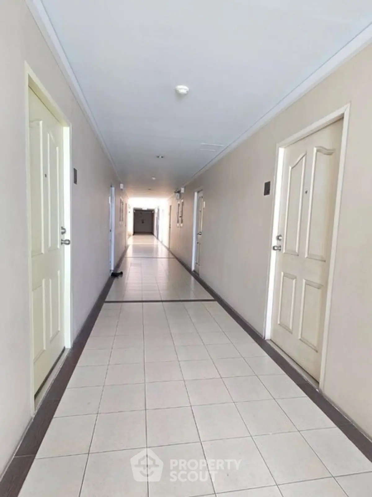 Spacious and well-lit apartment corridor with tiled flooring and multiple doors.