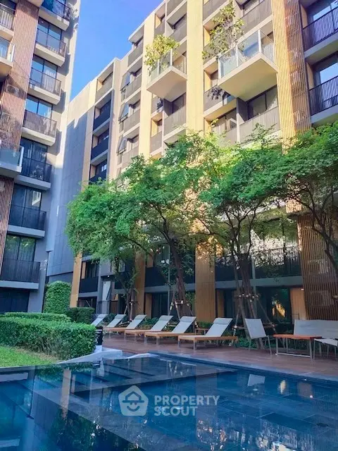 Luxurious modern apartment complex with pool and lush greenery