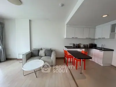 Modern open-layout living room with kitchen, featuring sleek furniture and bright accents.