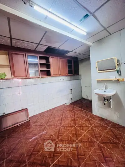 Spacious kitchen area with tiled flooring and wooden cabinets, ideal for renovation.