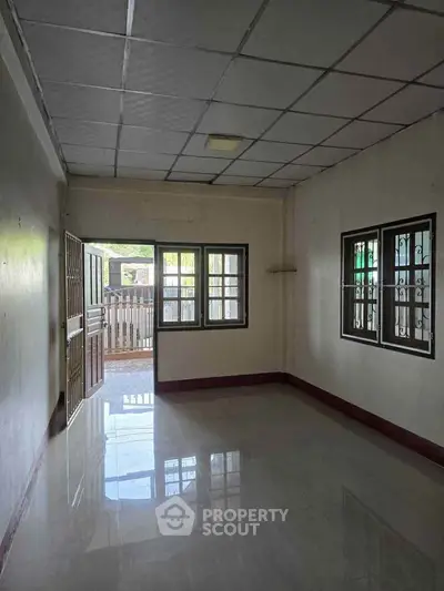Spacious empty room with tiled floor and large windows, ideal for customization.