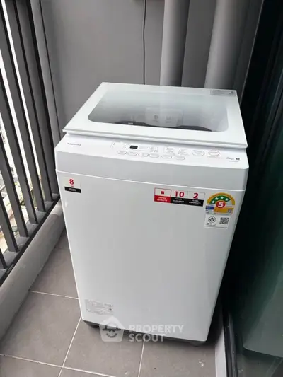 Modern washing machine on a balcony with sleek design and energy efficiency labels.
