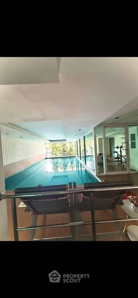 Luxurious indoor pool with modern design and gym view, perfect for relaxation and fitness enthusiasts.