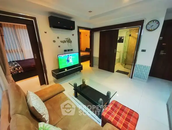 Modern living room with TV, sofa, and open view to bedroom and bathroom.
