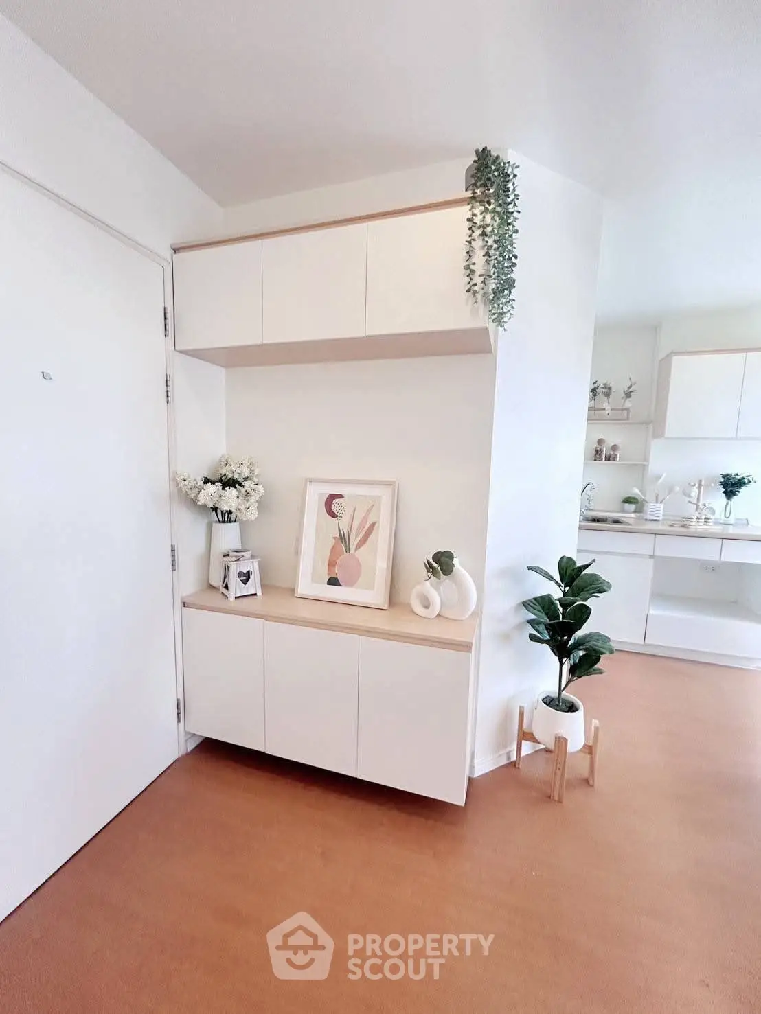 Modern minimalist interior with white cabinets and decorative plants, showcasing a stylish and inviting home entryway.