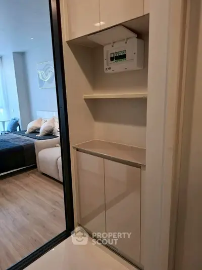 Modern apartment interior with sleek storage and view into a cozy bedroom.