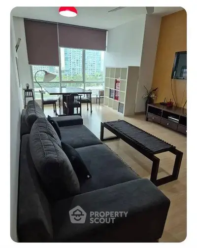 Modern living room with large windows and stylish furniture in a high-rise apartment.