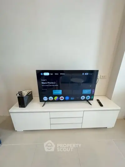 Modern living room with sleek TV setup on white console, perfect for entertainment.