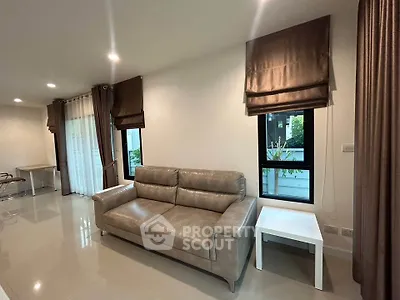Spacious living room with modern leather sofa and elegant curtains in a bright, airy setting.