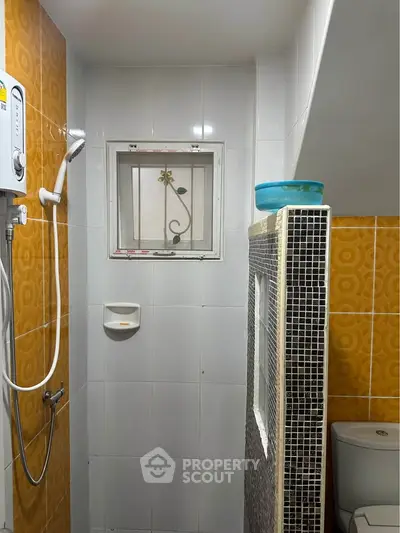 Compact bathroom with shower and toilet featuring vibrant orange tiles.