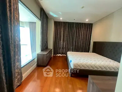 Spacious bedroom with elegant hardwood floors and luxurious drapery