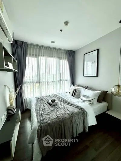 Modern bedroom with stylish decor and large window offering natural light
