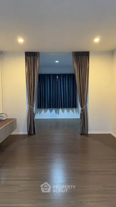 Spacious modern interior with elegant curtains and wooden flooring, perfect for stylish living.