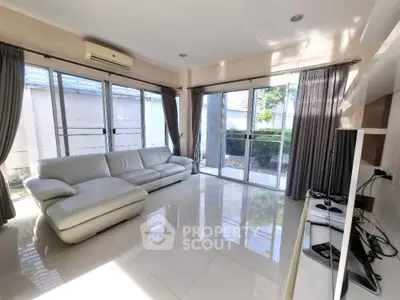 Spacious living room with large windows and modern white sofa, offering abundant natural light.