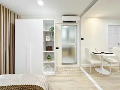 Modern bedroom with sleek white furniture and cozy dining area