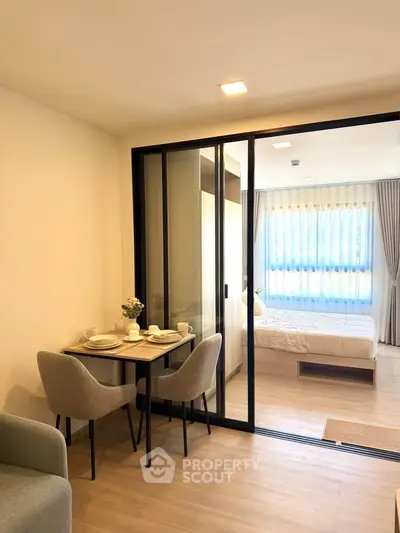Modern studio apartment with glass partition, cozy dining area, and bright bedroom.