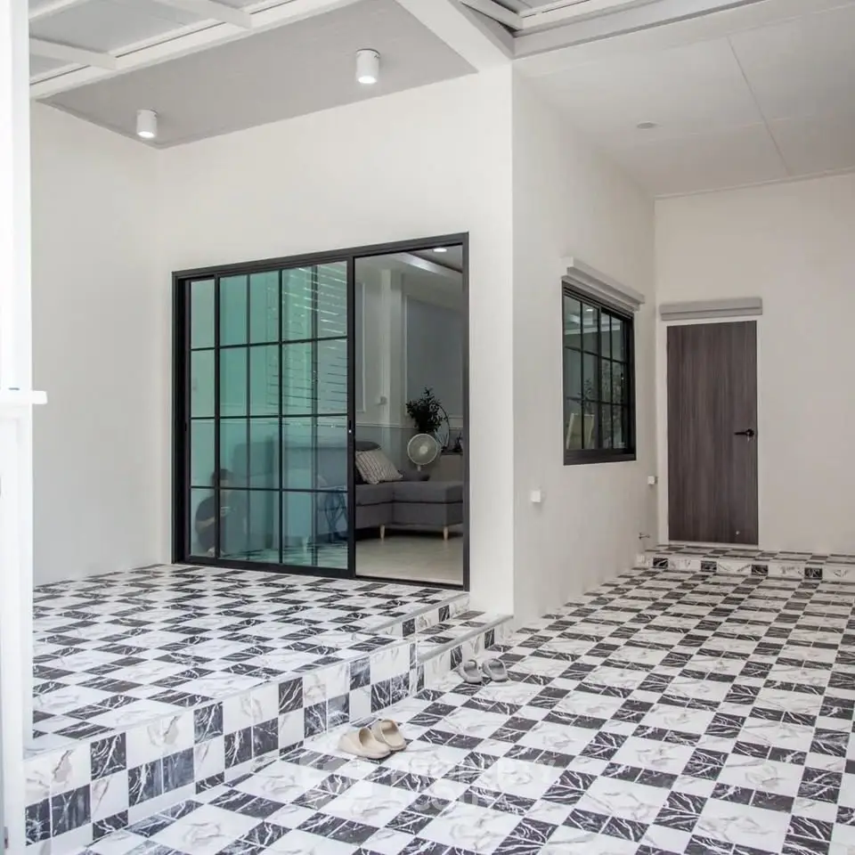 Modern home entrance with stylish black and white tiled flooring and glass sliding doors.