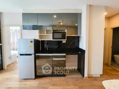 Modern kitchen with sleek cabinetry, stainless steel fridge, and built-in microwave in stylish apartment.