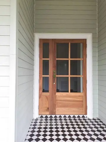 Charming wooden front door with glass panels and stylish checkered tile entryway.