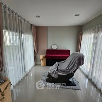 Spacious sunlit room with floor-to-ceiling windows and modern recliner chair.