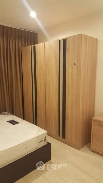 Cozy bedroom with wooden wardrobe and comfortable bed in modern apartment.