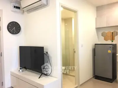Modern apartment interior with sleek TV setup and compact kitchen area.