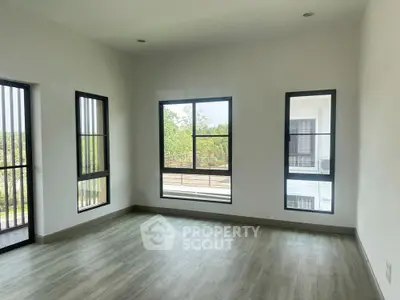 Spacious room with large windows and modern flooring, ideal for natural light lovers.