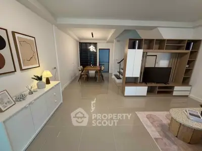 Modern living room with stylish decor and open dining area, featuring sleek furniture and contemporary design.