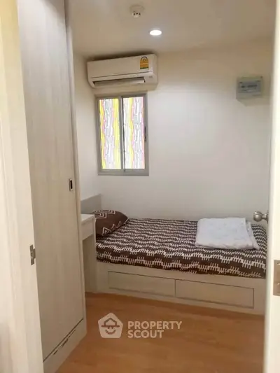 Cozy small bedroom with single bed and air conditioning in modern apartment.