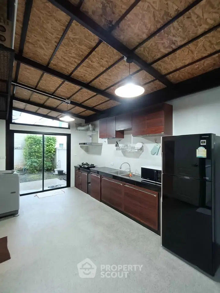 Spacious kitchen with modern appliances and open layout, featuring sleek cabinetry and large windows.