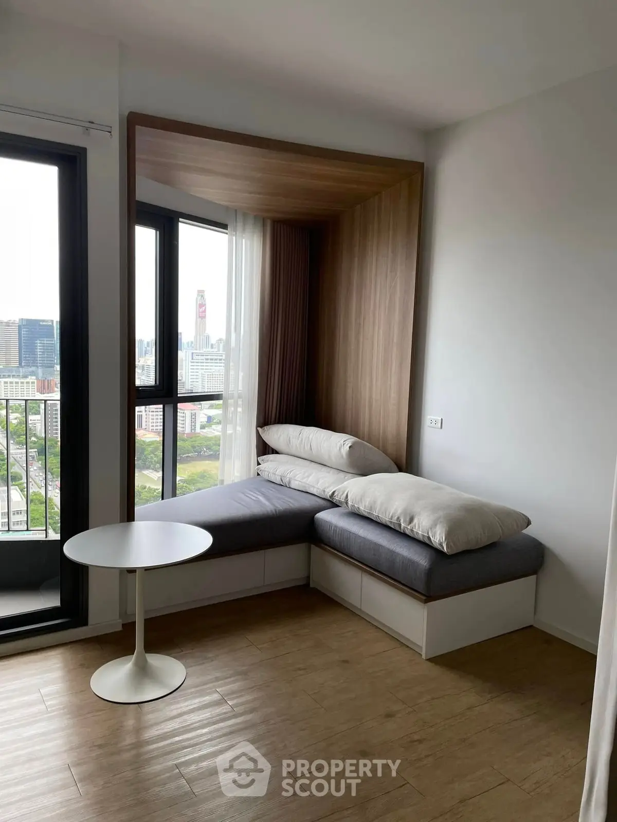Modern apartment with cozy window seating and city view, perfect for relaxation and enjoying the skyline.