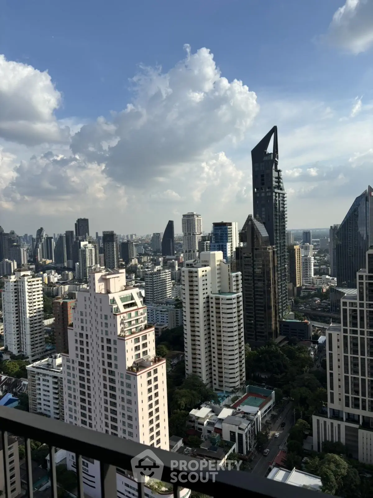 Stunning cityscape view from high-rise balcony with modern skyscrapers and blue sky.