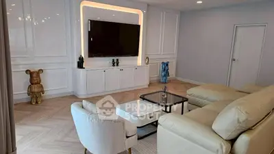 Elegant living room with modern decor and large TV, perfect for relaxation.