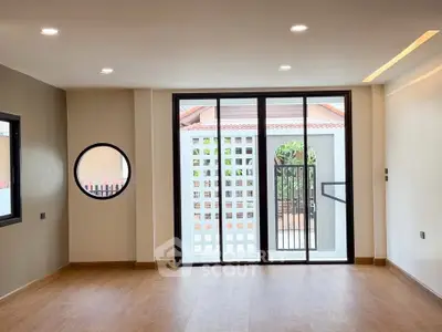 Spacious modern living room with large windows and wooden flooring, perfect for natural light lovers.
