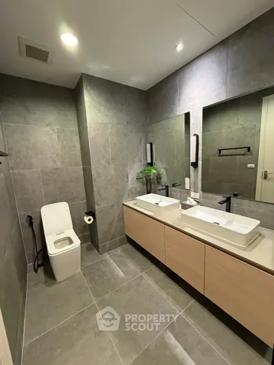 Modern bathroom with dual sinks and sleek gray tile design