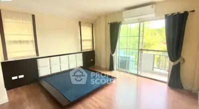 Spacious bedroom with large windows and balcony access, featuring hardwood floors and modern air conditioning.