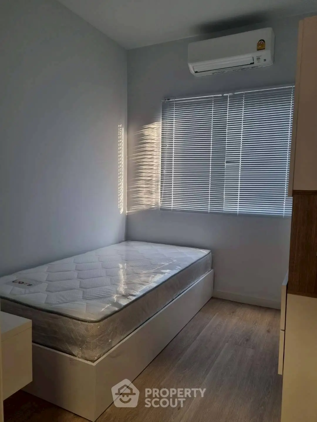 Cozy minimalist bedroom with single bed and air conditioning, perfect for a peaceful retreat.