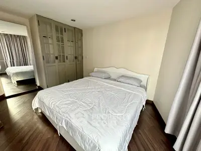 Spacious bedroom with elegant wooden flooring and large mirrored wardrobe