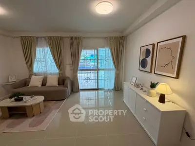 Spacious living room with modern decor and natural light, featuring a cozy sofa and stylish artwork.
