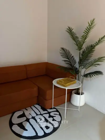 Cozy living room with modern orange sofa, stylish side table, and decorative plant for a relaxing ambiance.