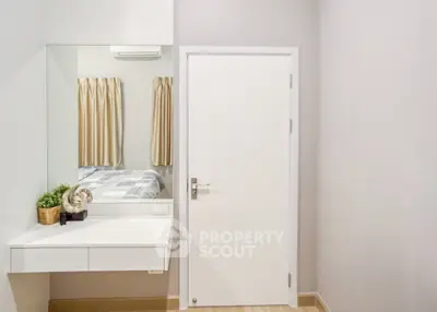 Minimalist bedroom with white door and built-in vanity mirror