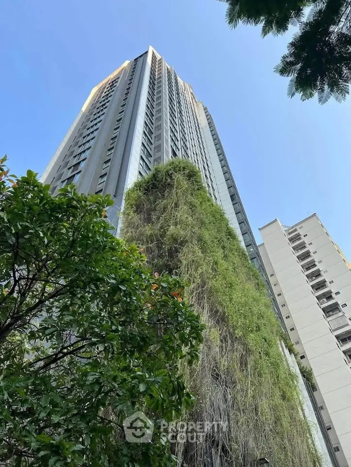 Stunning high-rise building with lush greenery and clear blue sky