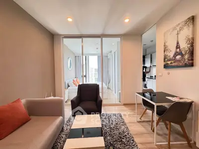 Modern living room with stylish furniture and open layout leading to bedroom and kitchen.