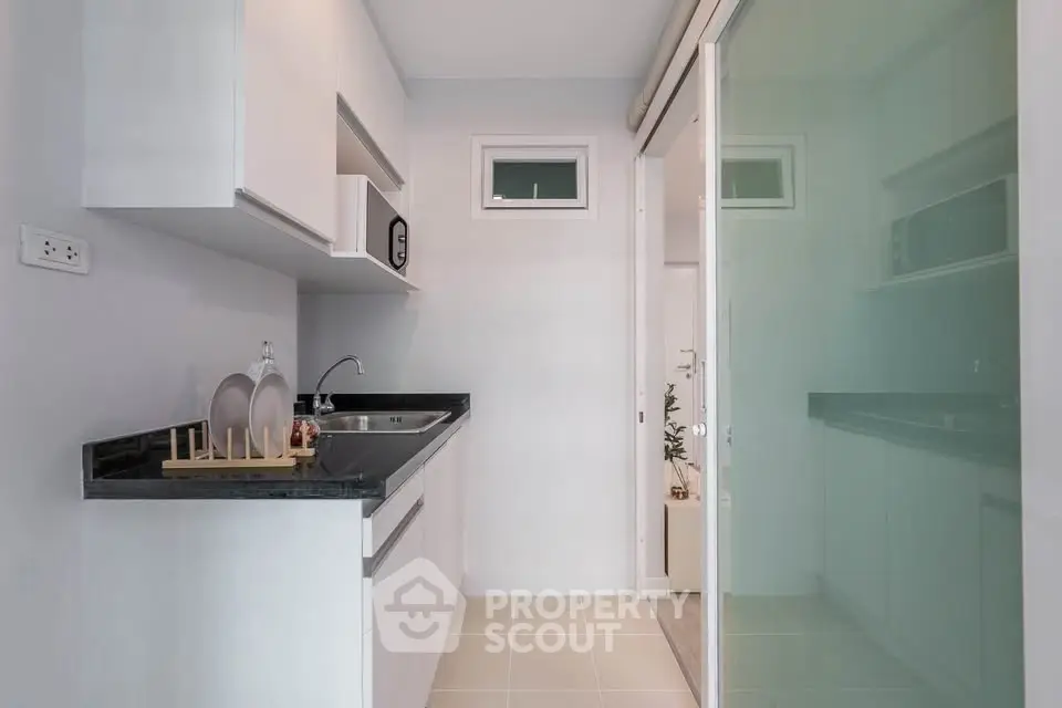 Modern kitchen with sleek cabinetry and black countertops in a compact layout.