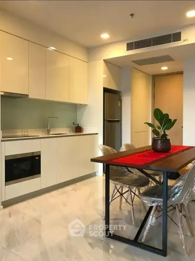 Modern kitchen with sleek cabinetry and dining area in contemporary apartment.